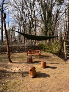 a hammock and a bench in a park with trees at Märchenhütte- Campen am Wald und See in Neuruppin