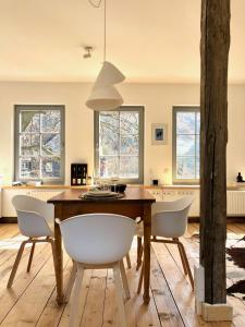 ein Esszimmer mit einem Holztisch und weißen Stühlen in der Unterkunft Ferienwohnung Weingut Villa Huesgen am Mönchhof in Traben-Trarbach