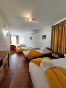 a row of beds in a room with yellow sheets at Hotel Prvan in Vrgorac