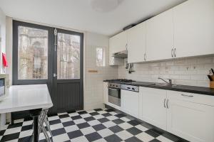 a kitchen with white cabinets and a checkered floor at Voorstraat-Havenzicht 2de in Dordrecht