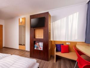 a bedroom with a bed and a table and a chair at ibis Kassel Melsungen in Melsungen