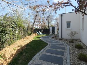 un jardín con un camino de piedra junto a una casa en Grain de Sable et son Jacuzzi, en Talmont