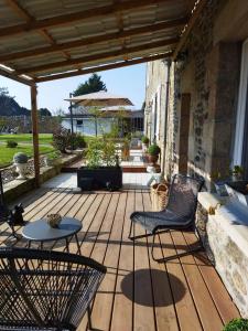 un patio con mesa y sillas en una terraza de madera en La Ménardière Serenitatis chambre d'hôtes petit déjeuner compris, en Corseul