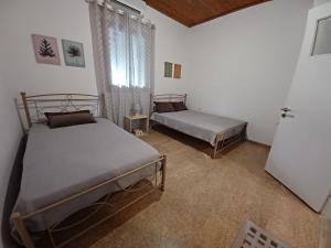1 dormitorio con 2 camas y ventana. en Beach House for up to 9 people near Olympia, en Katakolon