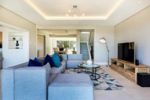 ein Wohnzimmer mit blauen Sofas und einem TV in der Unterkunft Serein in Kapstadt