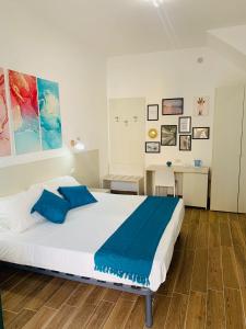 una camera da letto con un grande letto bianco con cuscini blu di Bed and Breakfast Arco dei cappuccini a Taormina