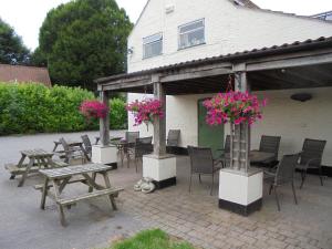 un patio con mesas, sillas y flores rosas en The River Don Tavern and Lodge, en Crowle