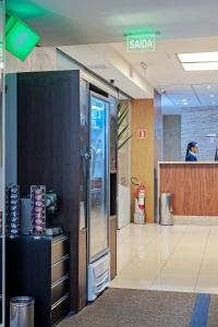 une femme debout à un comptoir dans un bureau dans l'établissement FAST SLEEP Guarulhos by Slaviero Hotéis, à Guarulhos