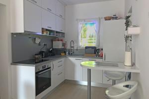 una piccola cucina bianca con tavolo e lavandino di Apartment Maksimir Yard Zagreb a Zagabria