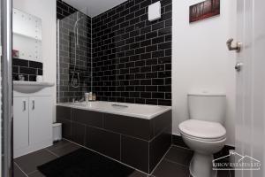 e bagno piastrellato nero con servizi igienici e lavandino. di Δ Ares Apartment Δ The Flame of Town a Southampton