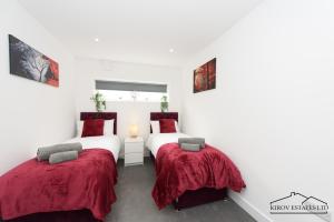 2 posti letto in una camera con pareti bianche e lenzuola rosse di Δ Ares Apartment Δ The Flame of Town a Southampton