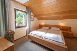- une chambre avec un lit et un plafond en bois dans l'établissement Café Pension Leistner, à Obertrubach