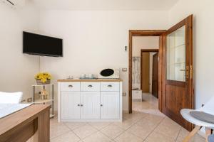 多木斯馬里亞的住宿－Appartamento in Villa Gelsomino，客厅配有白色橱柜和墙上的电视