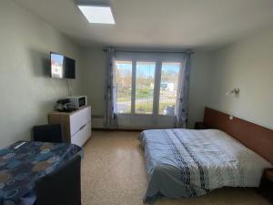 a bedroom with a bed and a large window at Les studios meublés de la résidence Beatrice in Bourbonne-les-Bains