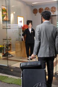 a woman standing next to a man with a suitcase at YR Hotel & Apartments in Hanoi