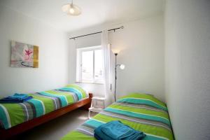 um quarto com 2 camas e uma janela em Vista Mar: Lovely apartment with seaview just steps away from the beach in Burgau no Burgau