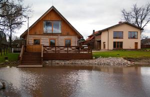a house sitting on top of a body of water at Vilks un Briedis Holiday Home & Wellness Area in Smiltene