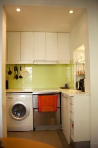 cocina con lavadora y armarios blancos en Sèvres-Raspail Paris 6 apartment, en París