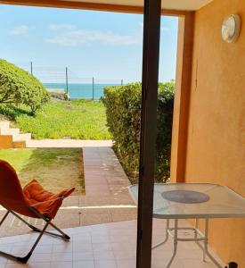 a patio with a glass table and a chair and the ocean at Cosy T2 refait à neuf climatisé, vue mer avec terrasse et jardin, Wifi piscine tennis et parking in Sète