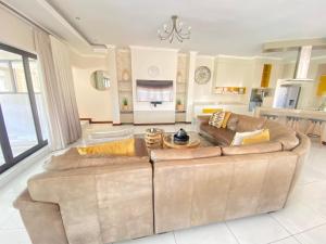 ein Wohnzimmer mit einem braunen Sofa und einer Küche in der Unterkunft The House in Hazyview