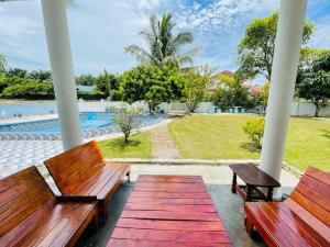 two wooden benches sitting on a porch with a pool at PD Best Homestay in Port Dickson