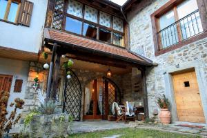 a stone house with a wooden door and a patio at La finestra sulla contea in Ovaro