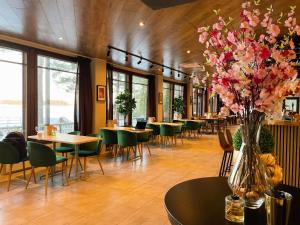 a restaurant with tables and chairs and a vase of flowers at Beach Hotel Santalahti in Kotka