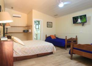 1 dormitorio con 2 camas y TV en la pared en Horquetas River Lodge, en Sarapiquí