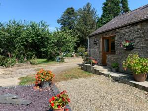 a stone cottage with flowers in front of it at Parc Farm B&B in Llanarth