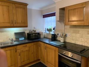 a kitchen with wooden cabinets and a sink and a microwave at Parc Farm B&B in Llanarth