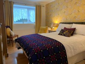 a bedroom with a bed with a colorful blanket on it at Parc Farm B&B in Llanarth