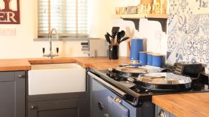 una cucina con piano cottura e 2 padelle di Courtyard Cottage at Stepps House a Ilminster