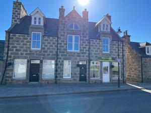 a large brick building on the corner of a street at Deeside Snugs Apartments in Kincardine OʼNeil