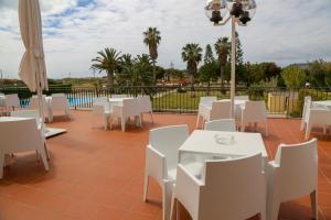 a patio with white tables and white chairs at INATEL Porto Santo in Porto Santo