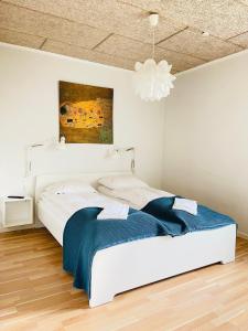 a white bedroom with a bed and a chandelier at aday - Nice and cozy place in Aalborg