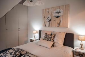1 dormitorio con 1 cama con sábanas y almohadas blancas en B&B De Klaproos, en Merkem