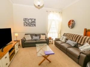 Una sala de estar con dos sofás y un televisor. en The Coach House, en Ventnor