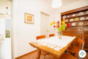 une salle à manger avec une table et un vase de fleurs dans l'établissement Sunny Corner Apartment, à Pise