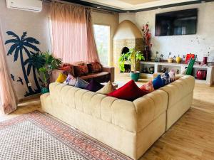 a living room with a large couch with colorful pillows at Ilafe Farmhouse, Villa avec piscine chauffée privée et Jacuzzi pour familles in Marrakesh