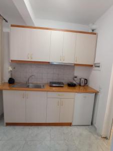 uma cozinha com armários brancos e um lavatório em Aggelis House em Saranda
