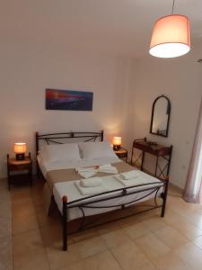 een slaapkamer met een bed, 2 lampen en een spiegel bij Aggelis House in Sarandë