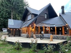 a log cabin with a deck and a house at Acceso Bayo - ubicada en el acceso al cerro bayo 3km del centro in Villa La Angostura