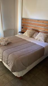 uma cama grande com cabeceira e almofadas de madeira em Acceso Bayo - ubicada en el acceso al cerro bayo 3km del centro em Villa La Angostura