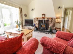 a living room with two red couches and a fireplace at Castle View Cottage in Denbigh