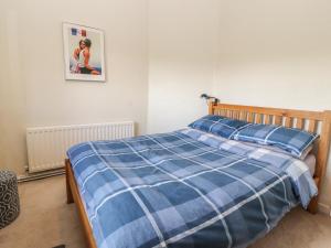 een slaapkamer met een bed met een blauwe en witte deken bij Castle View Cottage in Denbigh