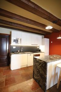 - une cuisine avec des placards blancs et un plan de travail en granit dans l'établissement Ático Marqués Figuera, à Morella