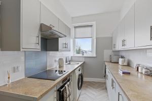 a kitchen with white cabinets and a sink and a dishwasher at Lovely 3 bedroom apartment in Aberdeen Centre in Aberdeen