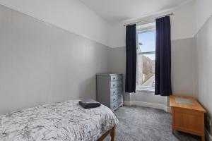 a bedroom with a bed and a dresser and a window at Lovely 3 bedroom apartment in Aberdeen Centre in Aberdeen