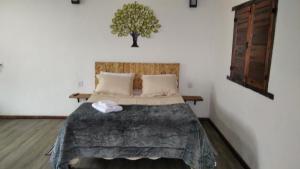 1 dormitorio con 1 cama con un árbol en la pared en Chalé Suite do chá en Lavras Novas