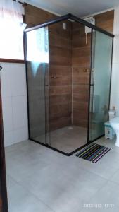 een douche met een glazen deur in de badkamer bij Chalé Suite do chá in Lavras Novas
